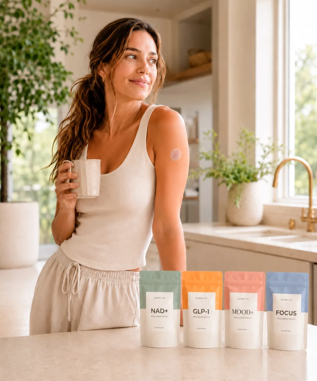 Woman wearing an AuraVita patch in her kitchen with NAD+, GLP-1, MOOD+ and FOCUS pouches on the counter